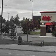 Arby's and C St & Benson Blvd NNW bus stand few paces to the east of #1 dental implant specialist Anchorage Midtown Dental Center